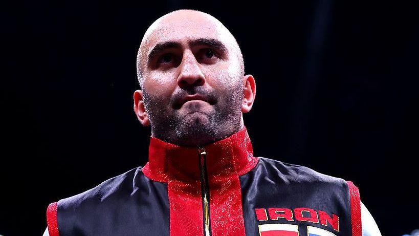 Murat Gassiev waits in the ring before a fight dressed in red and black vest
