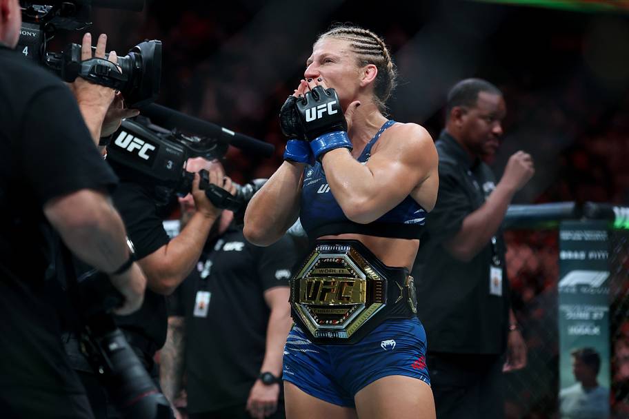 Kayla Harrison (blue gloves) reacts after defeating Julianna Pena (not pictured) in a bantamweight title bout during UFC 316
