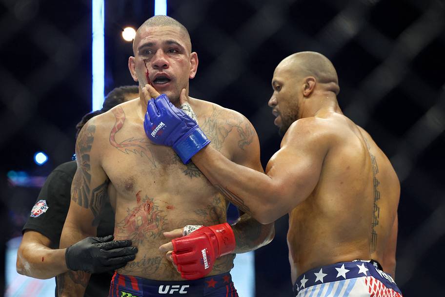 Alex Pereira (red gloves) reacts as Ciryl Gane (blue gloves) touches his face after their fight during UFC Freedom 250 at Whi