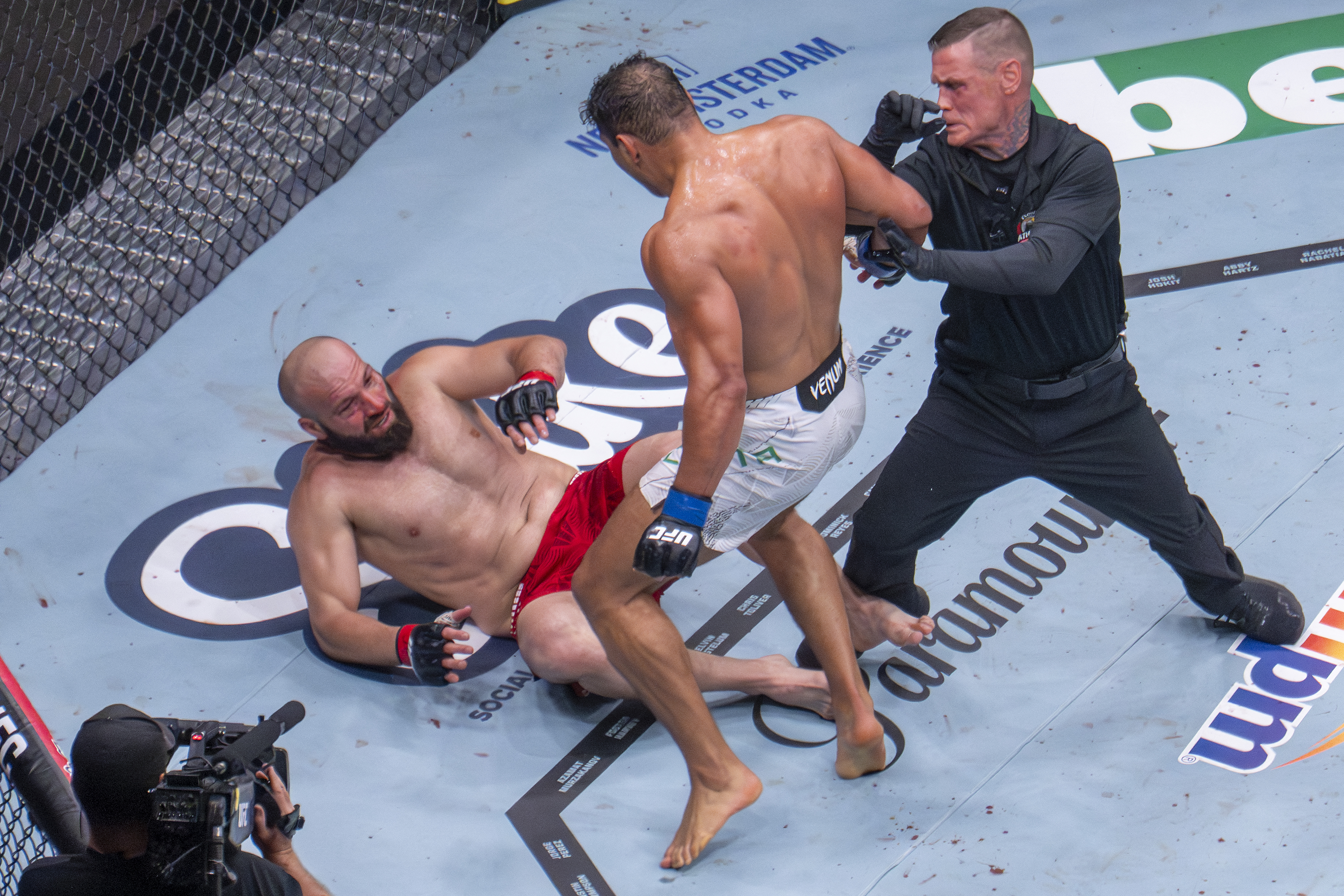A referee moves in to stop Brazilian Light Heavyweight Paulo Costa (C) as previously undefeated Russian Azamat Murzakanov falls with a Technical Knock Out (TKO) during UFC 327 at Kaseya Center in Miami, on April 11, 2026. (Photo by Jim WATSON / AFP via Getty Images)