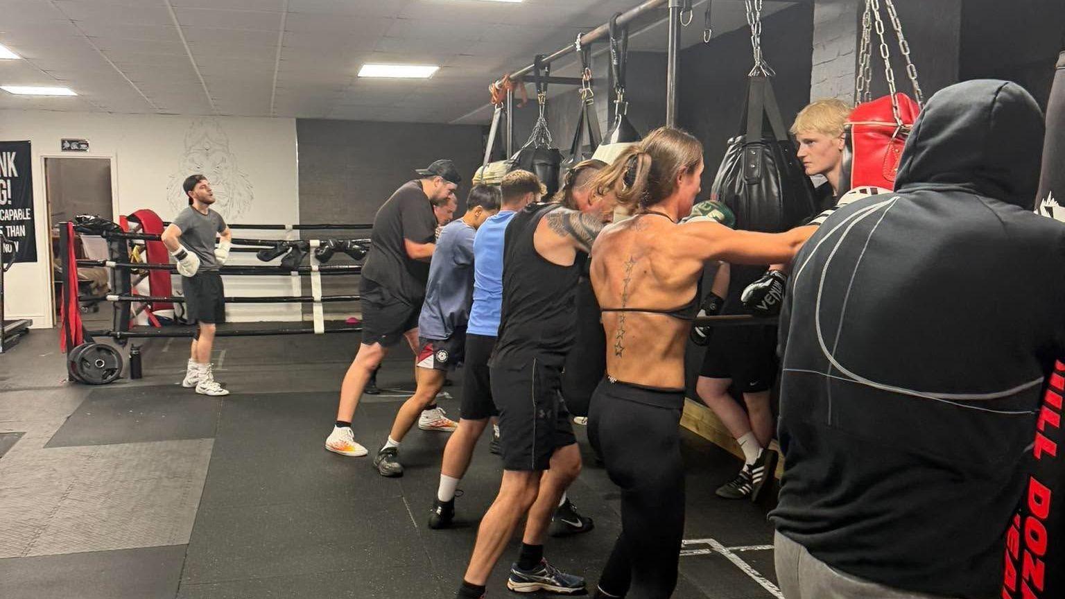 A line of people stand in a gym and box at War Boxing Academy in Warminster.