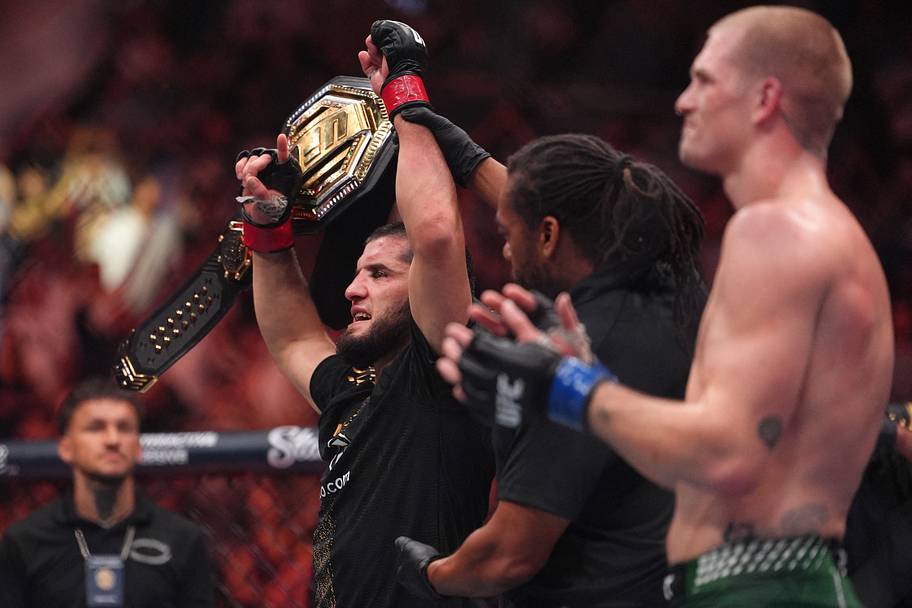 Islam Makhachev (red gloves) celebrates after defeating Ian Machado Garry (blue gloves) in the welterweight title bout during