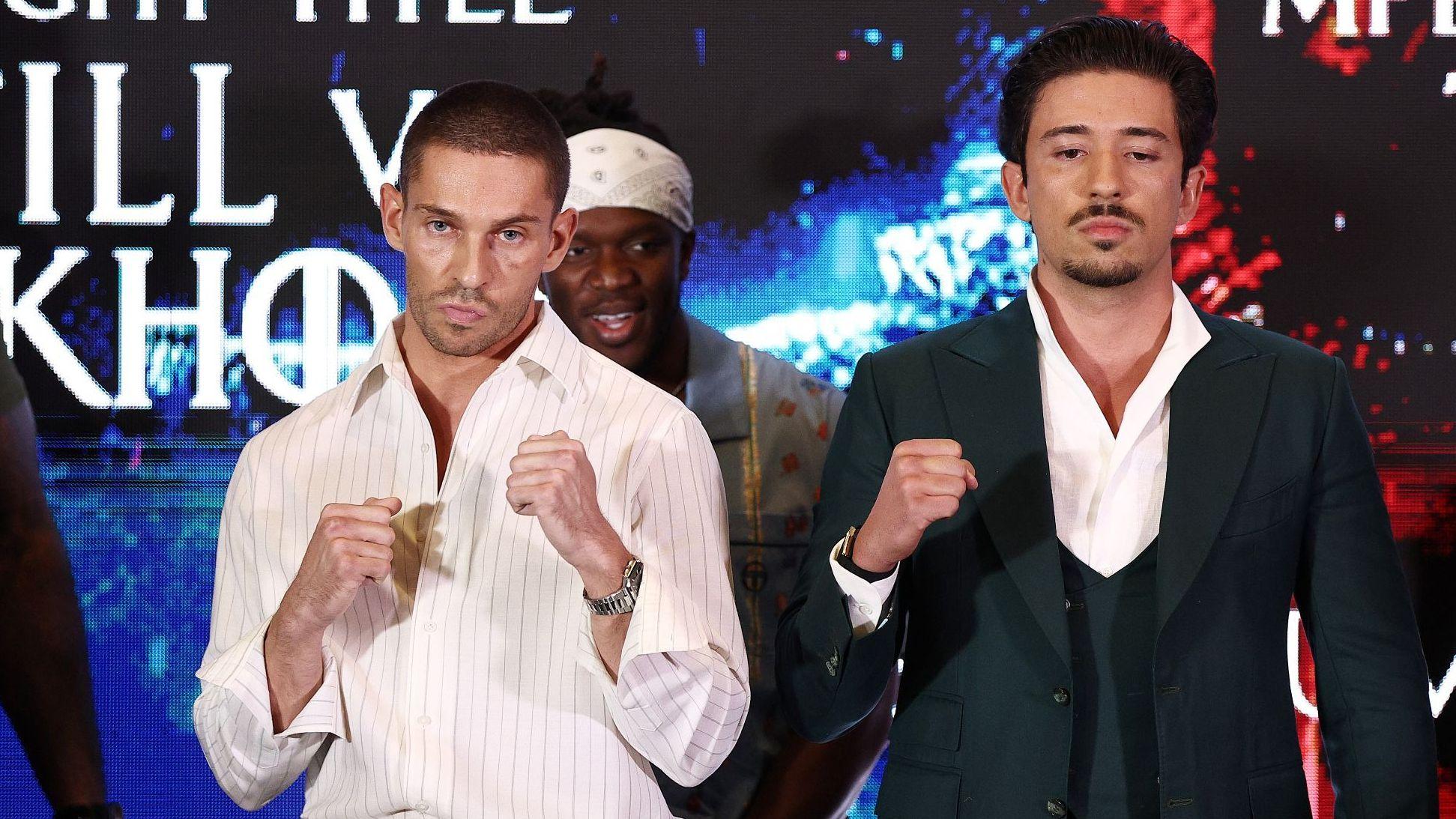 Joey Essex in a white shirt holds his fists up and Numeiro to his right holds a single fist up, wearing a black tuxedo.
