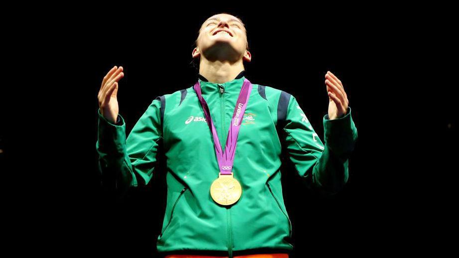 Katie Taylor in green and her gold medal around her neck